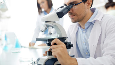 Mediziner sitzt vorm Mikroskop
