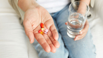 Frau nimmt Medikamente mit Wasser ein 