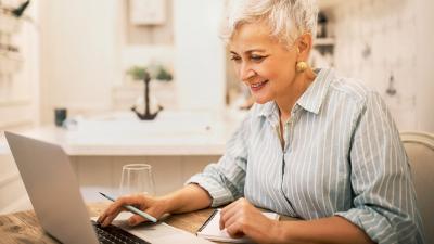 Seniorin schaut sich am Comptuer das Online-Seminar an 