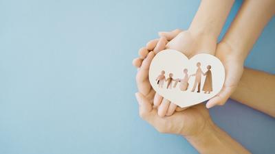 Hände halten eine Papierfamilie
