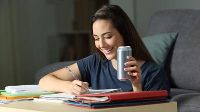 Frau trinkt auf dem Sofa ein Energy-Drink