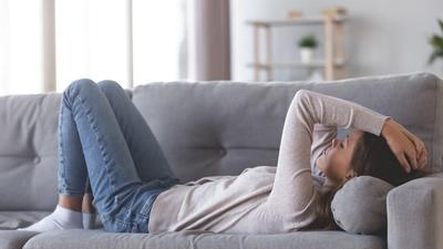 Frau liegt mit einer Herzmuskelentzündung auf dem Sofa