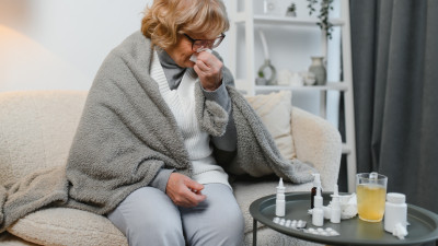 Frau sitzt stark erkältet auf dem Sofa