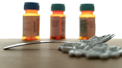 Löffel mit Medikamenten und im Hintergrund drei Medikamentenflaschen