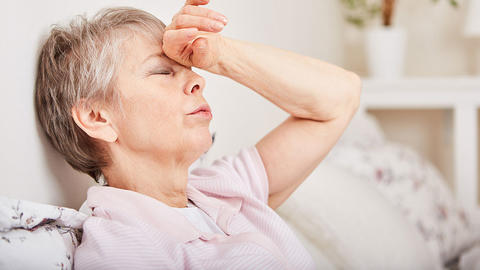 Frau liegt mit Schwindel im Bett