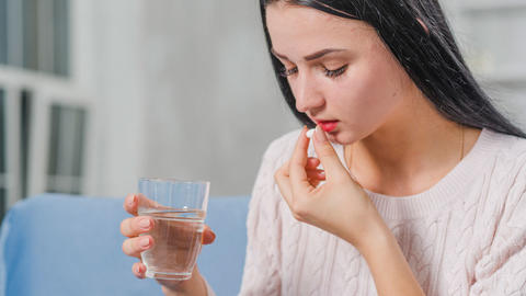 Frau nimmt Medikamente mit einem Glas Wasser ein. 