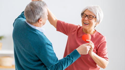 Mann und Frau tanzen mit einem Herz in der Hand