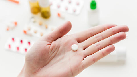 Abbildung einer geöffneten Hand, in der eine Pille liegt