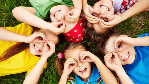 Kinder liegen im Gras und spielen