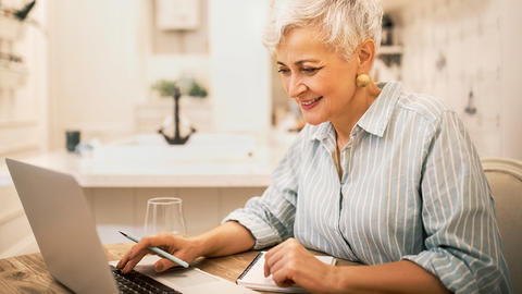 Seniorin schaut sich am Comptuer das Online-Seminar an