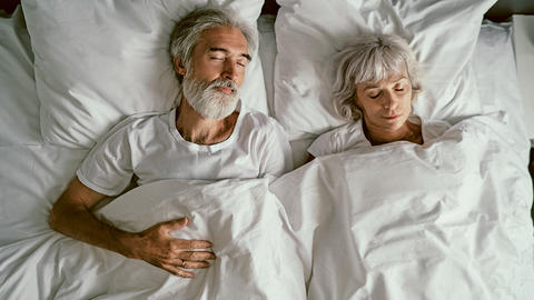 Ehepaar liegt im Bett und schläft