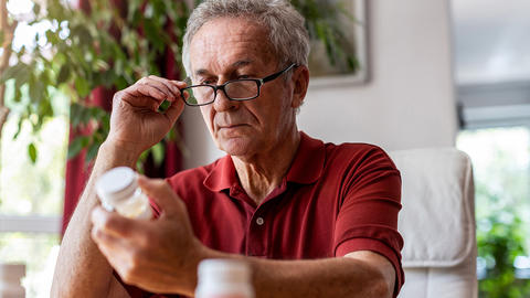 Mann schaut mit seiner Brille auf die Medikamentenpackung