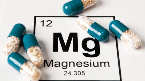 Magnesium Pillen liegen auf einem Bild der chemischen Abkürzung