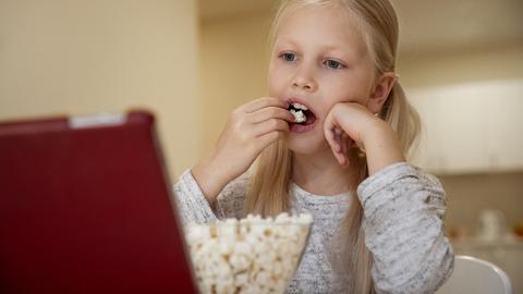 Mädchen schaut auf dem Tablet ungesunde Lebensmittelwerbung