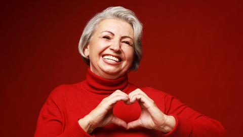 Frau in einem roten Pullover formt ein Herz