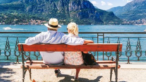 Ehepaar sitzt auf einer Bank und schaut auf den See