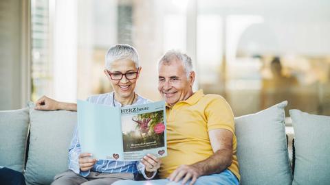 Ehepaar liest auf dem Sofa die neue Ausgabe der HERZ heute