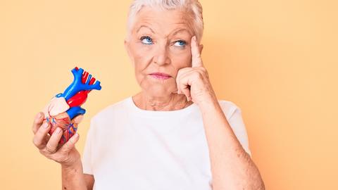 Frau ist nachdenklich und hat ein Herz in der Hand