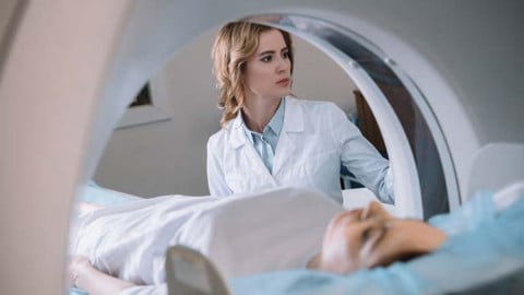 Junge Patientin liegt in CT-Röhre, Ärztin bewacht den Vorgang.